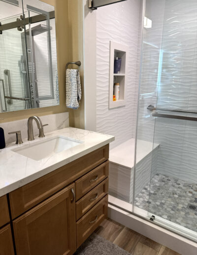 A stunning full bathroom remodel in Bellflower, CA, by CALbath Renovations, featuring a floating double vanity, quartz countertops, and a spacious walk-in shower.