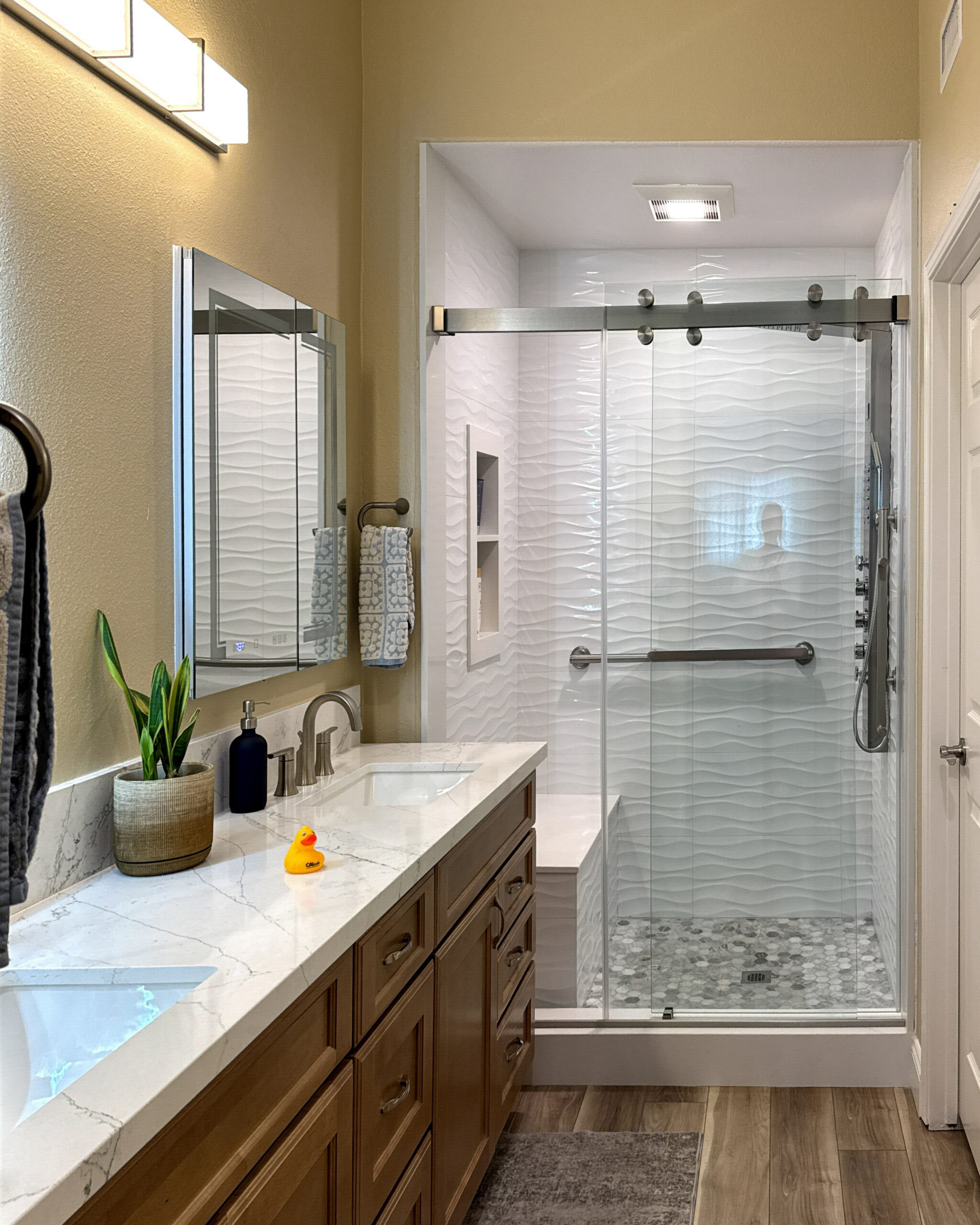 Bright bathroom renovation with white acrylic walls and chrome fixtures by CALbath Renovations
