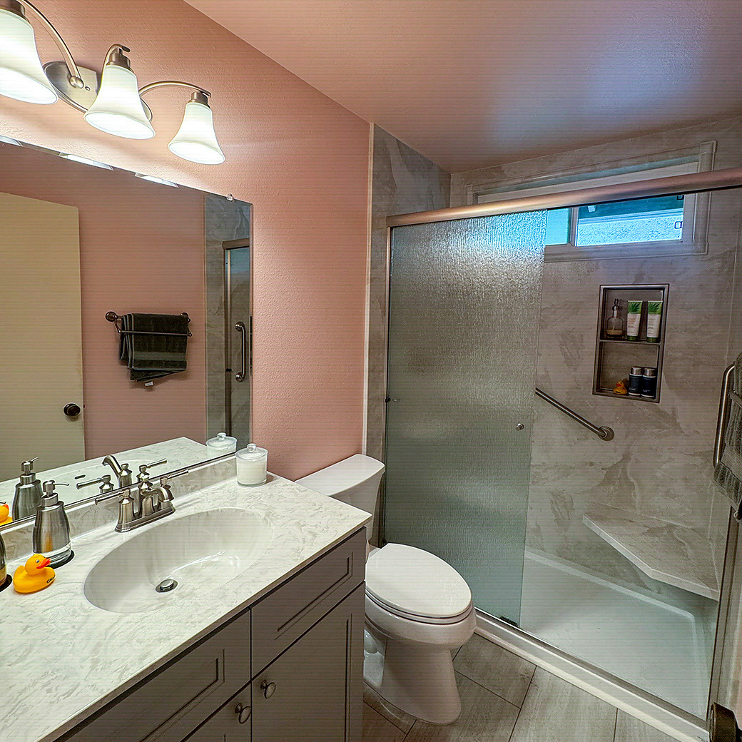 Low-maintenance bathroom remodel with a glass shower door and stone-look tile by CALbath Renovations