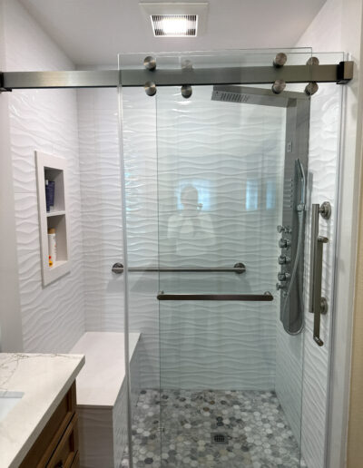 Modern full bathroom remodel in Norwalk with a freestanding soaking tub, wood-style vanity, and custom tile work by CALbath Renovations.